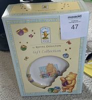 The unopened box containing the Royal Doulton Classic Pooh porcelain plate with visible Classic Pooh and Winnie the Pooh themed design on packaging.