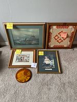 Five framed paintings and decorative glass plate grouped on floor, showing full lot contents