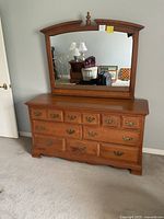 Front view of traditional wooden dresser with attached arched mirror showing drawer handles and finish.