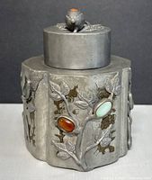 Front view showing pewter tea caddy, relief branches, red and green cabochon stones, lid on