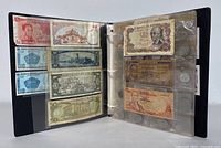 Open binder showing various banknotes (Spain, Costa Rica, etc.) left page and coins right page