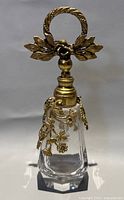 Full view front of crystal perfume bottle with brass floral overlay and stopper