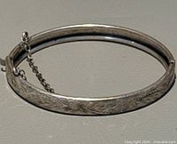 Overall view of closed sterling silver bangle with floral engraving