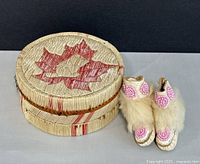 Box closed beside moccasins showing quill maple leaf design and fur trim
