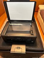Photo of the Epson XP-200 printer with the scanner lid open showing clean scanner glass and paper tray extended.