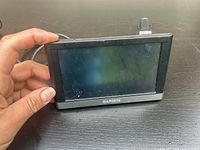 Front view of Garmin nüvi 2597LMT GPS device held in hand showing the touchscreen with minor scratches and smudges.