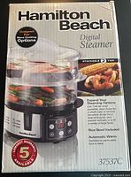 Front of Hamilton Beach Digital Steamer box showing product image, 2-tier stackable design, rice bowl inclusion, 5-year warranty, and digital control panel.