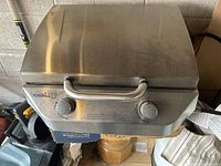 Front angled view of the closed stainless steel gas grill showing dual control knobs and handle.