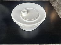 Closed white plastic salad spinner showing its neutral white finish and lid with press mechanism.