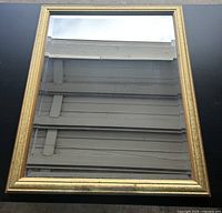 Photo of the rectangular vintage wall mirror with gold-tone ornate frame showing full mirror surface and frame details.