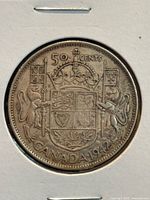 Reverse side of 1942 Canadian half dollar coin showing detailed Canadian coat of arms with lion and unicorn supporters, crown, flags, denomination and year.