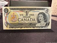 Front side of a 1973 Canadian one dollar bill with Crow Bouey prefix ECS serial number visible.