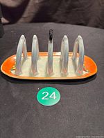 Front angled view of antique Noritake Japan lustreware toast rack showing its iridescent dividers and orange border