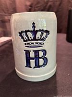 Front view of gray ceramic mug showing blue crown and HB logo