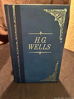 Front cover of the book in dark blue leather with gold embossed 'H.G. Wells' and decorative accents.