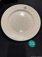 Full view of the round cream-colored vintage ceramic plate with visible age wear.