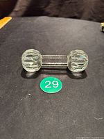 Photo showing full length of the crystal utensil rest shaped like a dumbbell on black fabric background with item number.