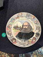 Full view of the round ceramic plate showing Shakespeare portrait at center and character portraits around the rim.