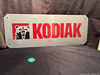 Full front view of the rectangular Kodiak Shoes plastic store sign on a dark fabric background.