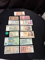 Shows full set of 13 assorted uncirculated paper money from various countries arranged on black background