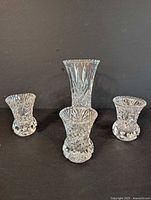Photo showing one large and three small crystal vases against a dark background.