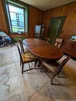 Full view of the oval solid oak dining table surrounded by 6 chairs in a vintage style room.