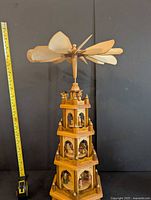 Full view of the tall wooden Asian windmill pyramid with a tape measure for scale showing about 26 inches tall.