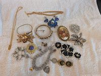 All costume jewelry pieces laid out on white towel showing full lot contents including different designs and colors.