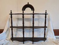 Full view of the three-tier wooden curio shelf showing turned finial posts and arched top