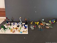 Two groups of various glass animal and flower figurines arranged on white and black backgrounds showing different shapes, colors, and details.