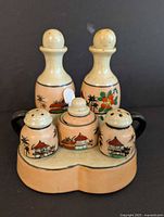 Front view of the set showing five shakers and jar on the tray, details of floral and Japanese house paintings.