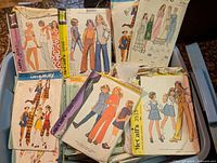 Large Rubbermaid bin filled with vintage sewing patterns for children and adults featuring illustrated covers.