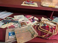 Overview of fabric pieces, embroidery hoops, ribbons and kits spread on table.