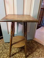 Front view of the 26-inch high occasional oak table showing the top, turned legs, and circular lower shelf.