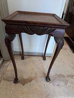 Front and side view of wooden occasional table showcasing carved apron and legs with claw feet.