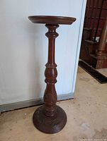 Full view of the wooden plant stand showing the circular top and detailed stem.