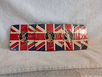 Set of four rectangular coasters featuring Queen Elizabeth II in a circular image overlaid on the Union Jack flag background, all still in plastic packaging