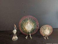 Three spun glass figurines on a black background, two peacocks and one stork.