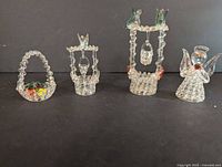 Full display of four spun glass decorative figurines on a black background showing size and detailing.