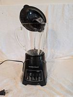 Full view of the black Hamilton Beach blender with glass pitcher and black lid.