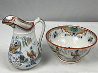 Photo showing the pitcher and bowl side by side displaying the Asian-inspired multicolor designs and orange rims.