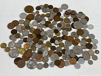 Full overview of various foreign coins spread out showing a range of sizes and metals including bronze, copper, silver, and brass.