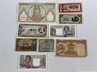 All nine foreign banknotes laid out on a white surface, showing full designs and condition.