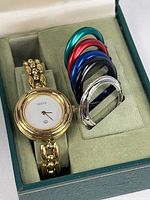 Watch and six bezel rings arranged in fitted green Gucci box