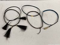 Five horse hair and leather hat bands laid on a white surface, showing variety in color and style.