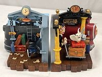 Front view of both Harry Potter 9 3/4 platform bookends showcasing the Hogwarts Express engine with character and luggage on one side, and stone archway with clock, ticket booth and luggage on the other.