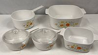 Full set of vintage CorningWare Wildflower casseroles and saucepans showing all five pieces on white surface.