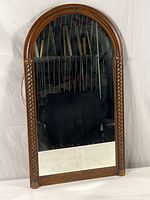 Full view of a vintage mirror with a round arched wooden frame and barley twist accents on each vertical side.