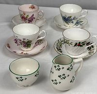 Group photo of four floral tea cups and saucers alongside clover cream pitcher and sugar bowl