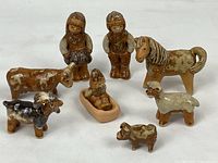 Full set of vintage Rutebo stoneware figurines depicting Jerk and Lisskulla along with five farm animals and a small child in a sled or basket, all with earth tone glazes.